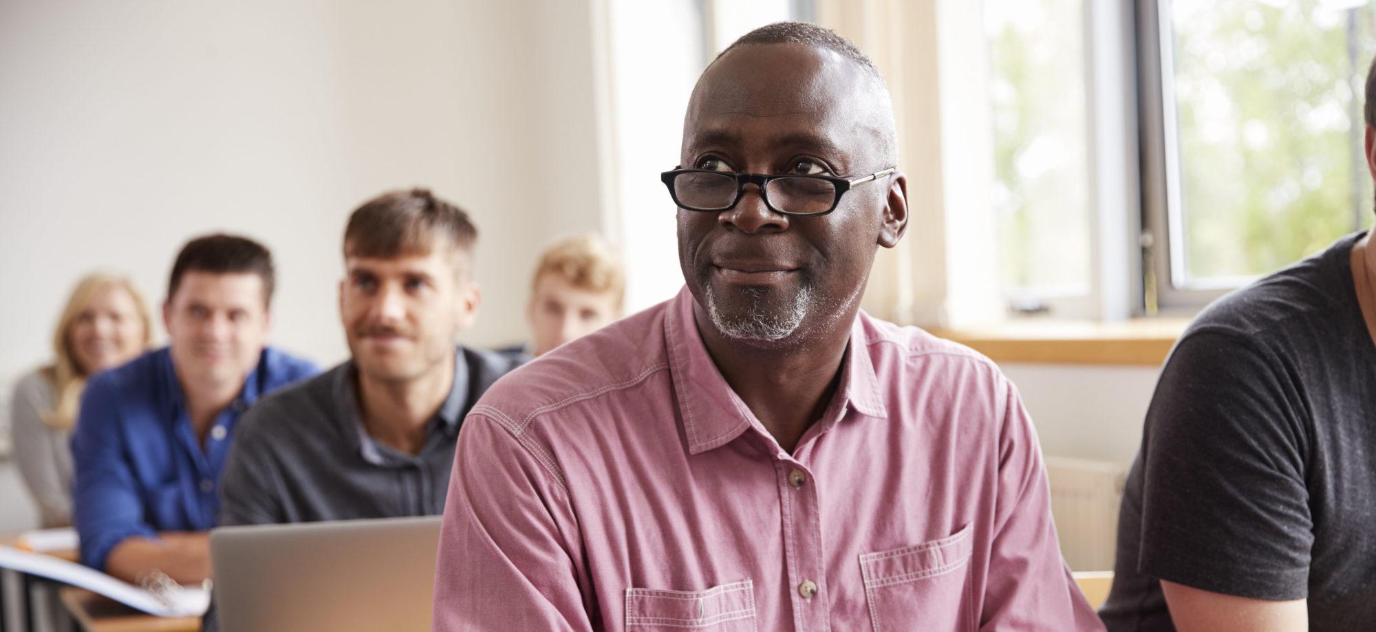 Mature Student Using Digital Tablet In Adult Education Class.