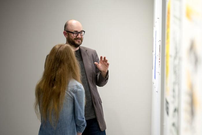 Male instructor explaining art exhibition.