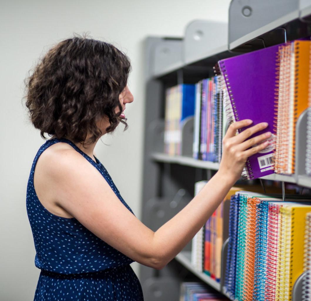 Lady picking out book at the library.