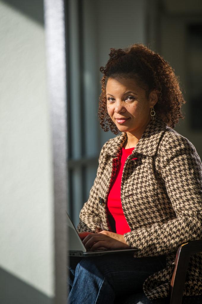 Woman looking at camera while working on laptop.