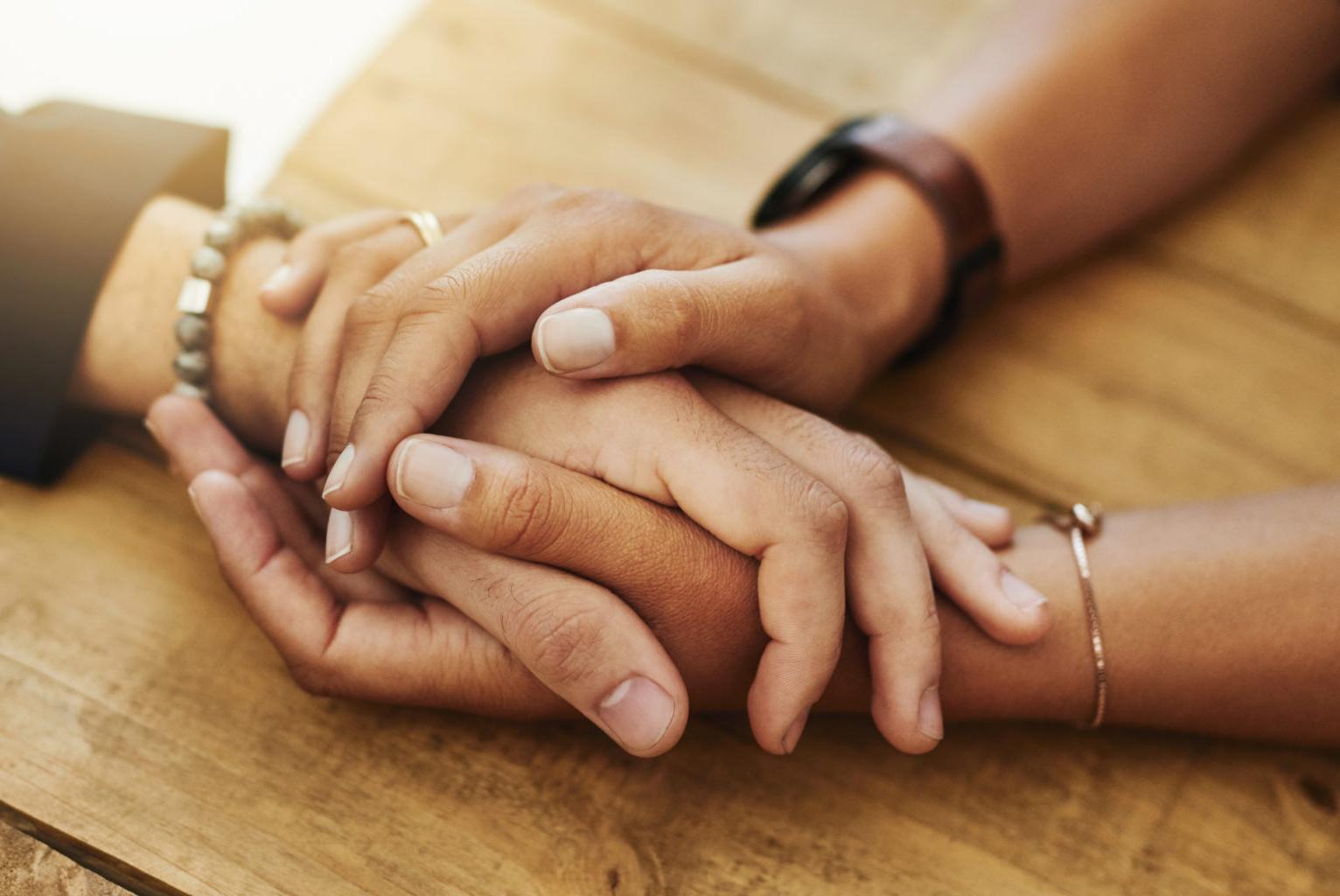 Two pairs of hands holding each other.