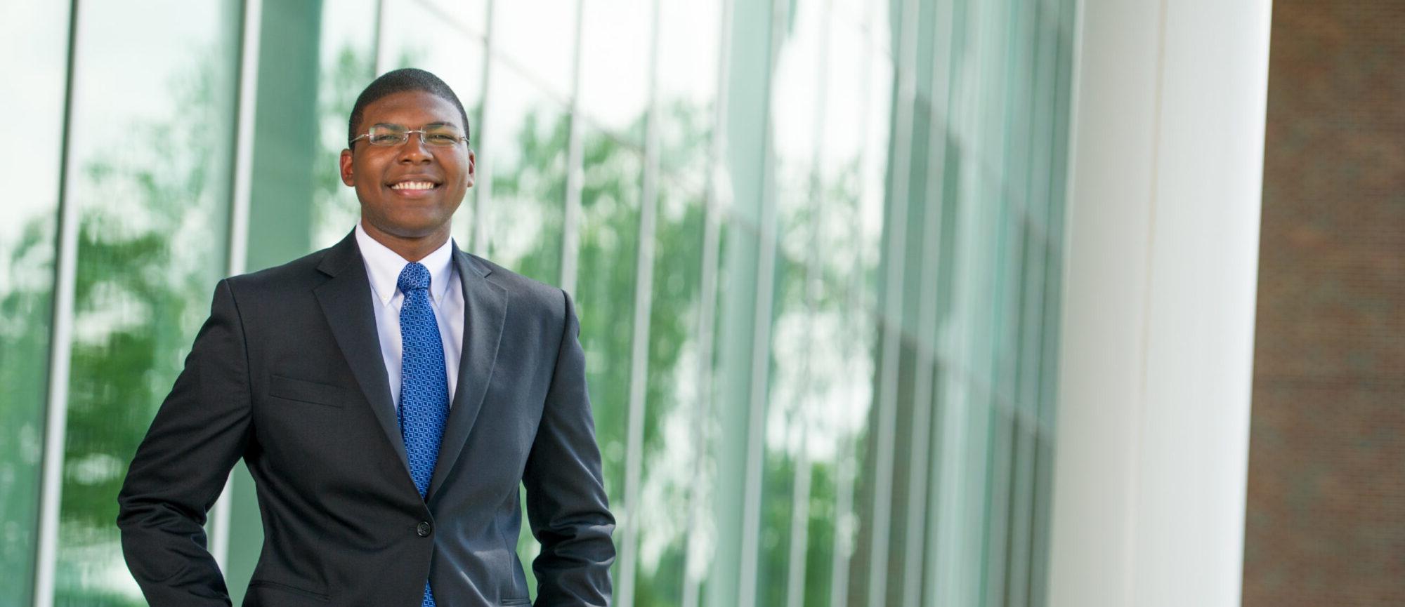 Man wearing professional attire with suit and blue tie.