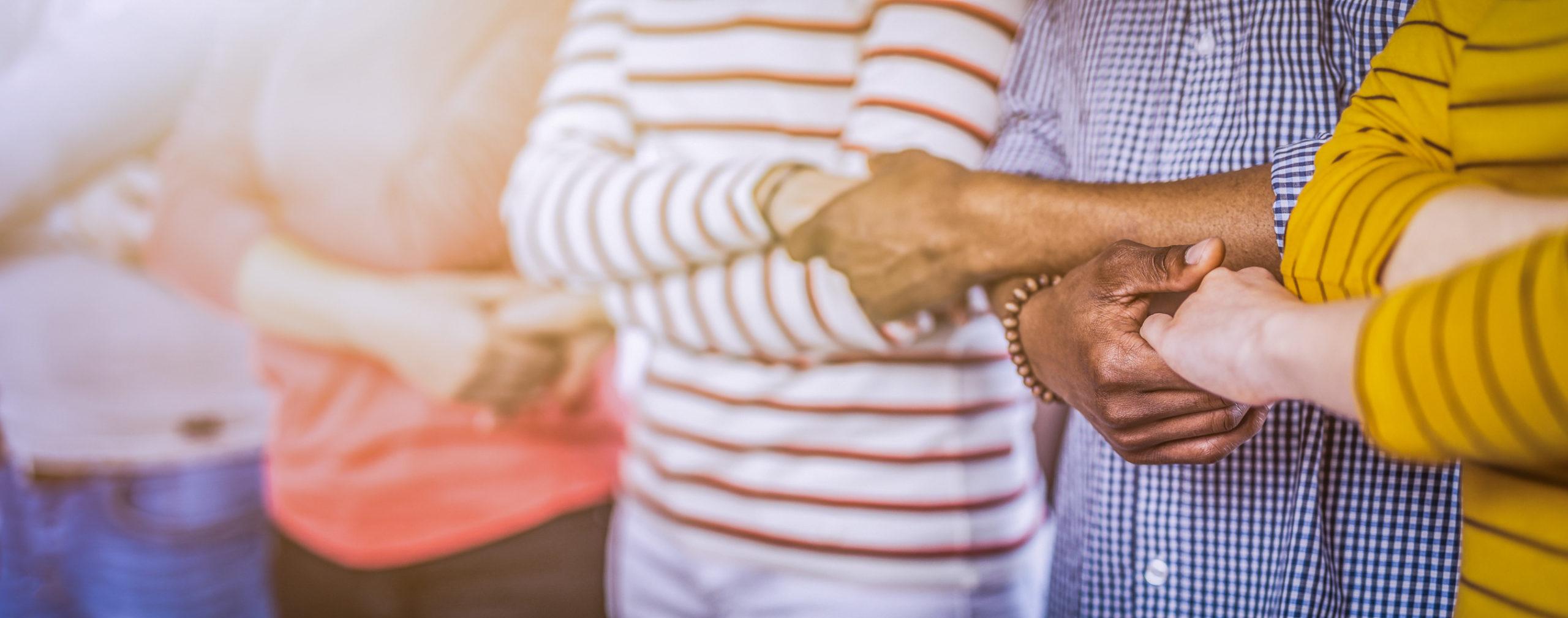 Creative team meeting hands together in line. Young people in casual clothes are holding hands. Unity and teamwork concept.