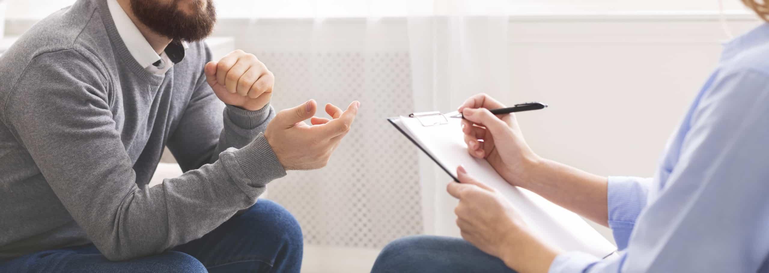 A male speaking with someone using a board talking about problems.