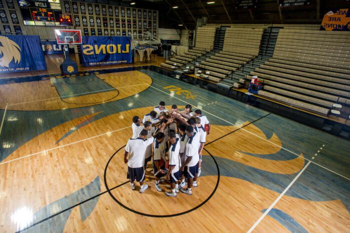 basketball team huddled around mid-court in practice.