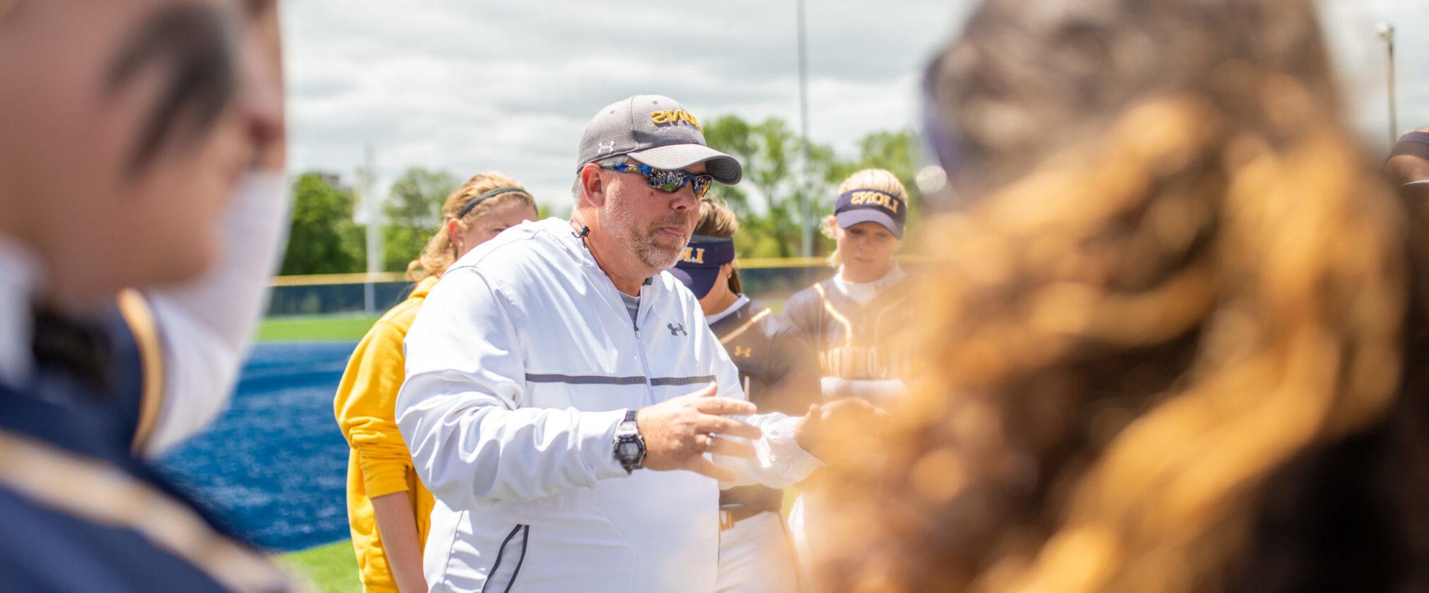 Coach instructing softball team.