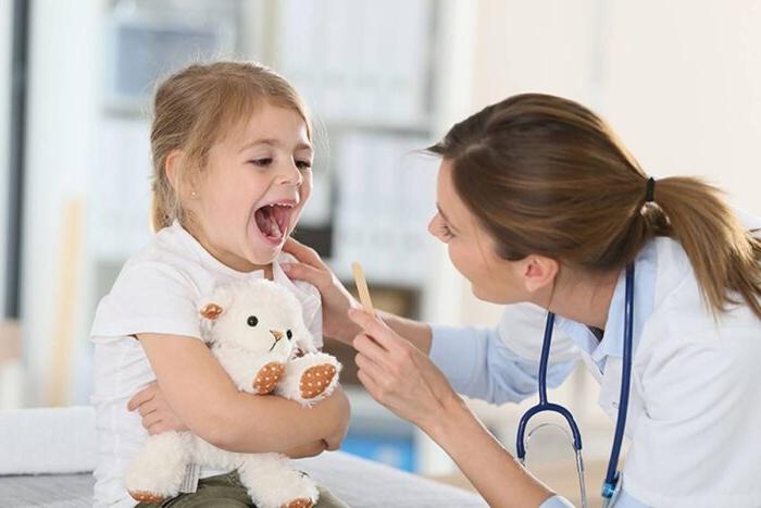 Nurse examining the mouth of a young patient.