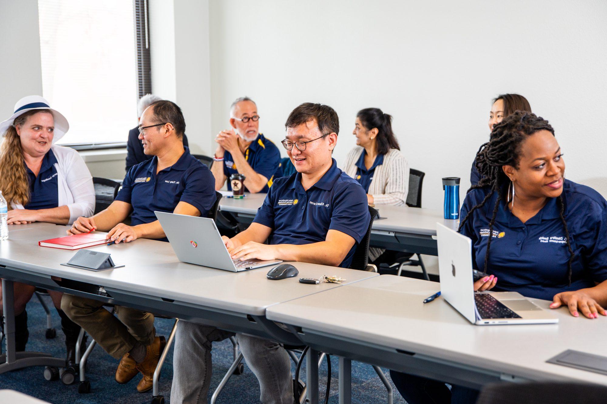 A group of Texas East Texas A&M faculty and staff engage in a collaborative meeting, working on laptops and discussing ideas.