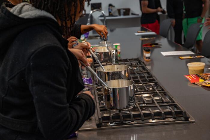 People cooking on a stove with metal pots